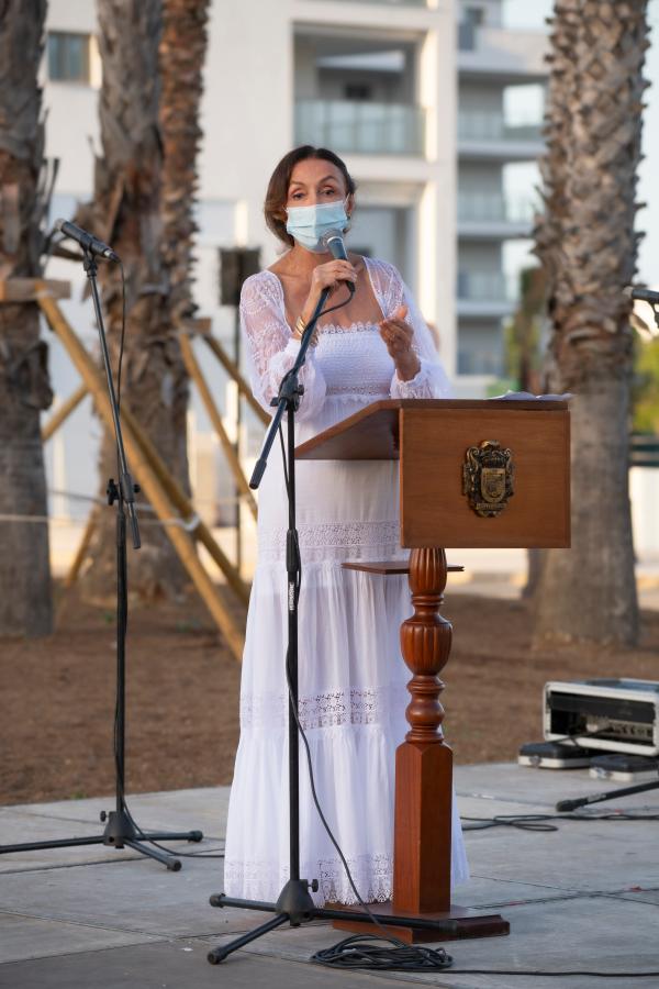 Esther Koplowitz en un escenario, detrás de un podio, pronunciando un discurso en memoria de las víctimas del Holocausto