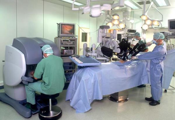 Equipo sanitario del Hospital Clínico San Carlos operando con el Robot Da Vinci en una sala de operaciones moderna