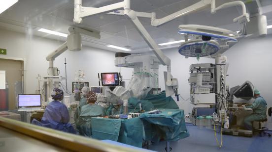 Profesionales de salud en una sala de operaciones, rodeados de grandes máquinas y el robot Da Vinci