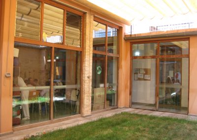 Cafetería de la Residencia La Nostra Casa, con grandes ventanales que ofrecen una vista relajante al jardín