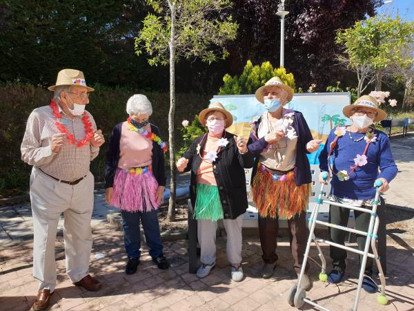 Residentes al aire libre, vestidos con collares de flores estilo hawaiano, bailando y disfrutando de una fiesta temática de verano