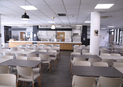 Una cafetería amplia y moderna, con varias mesas y sillas dispuestas