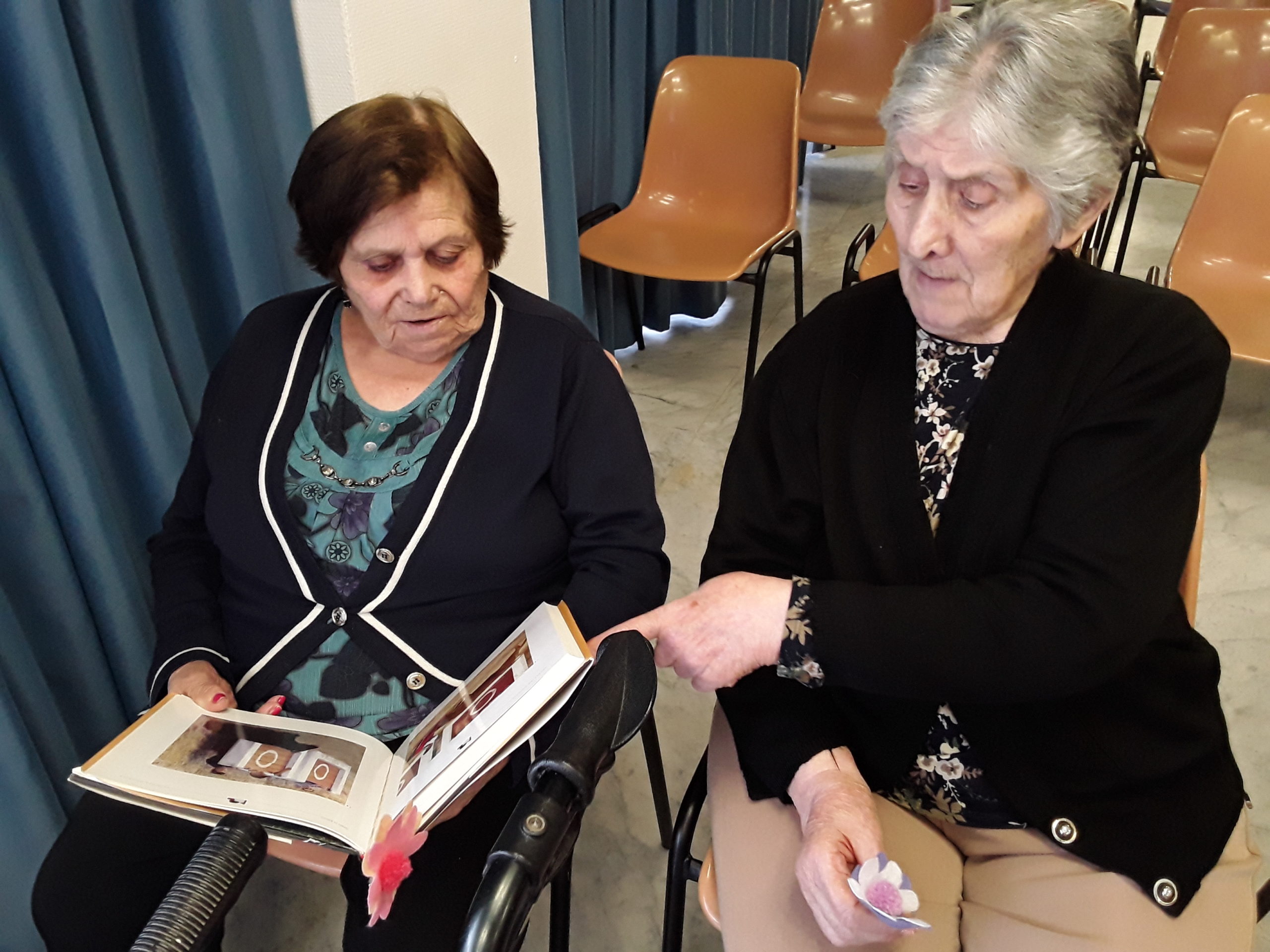 Dos residentas mirando imágenes en un libro, una de ellas señalando una imagen mientras la otra observa con atención