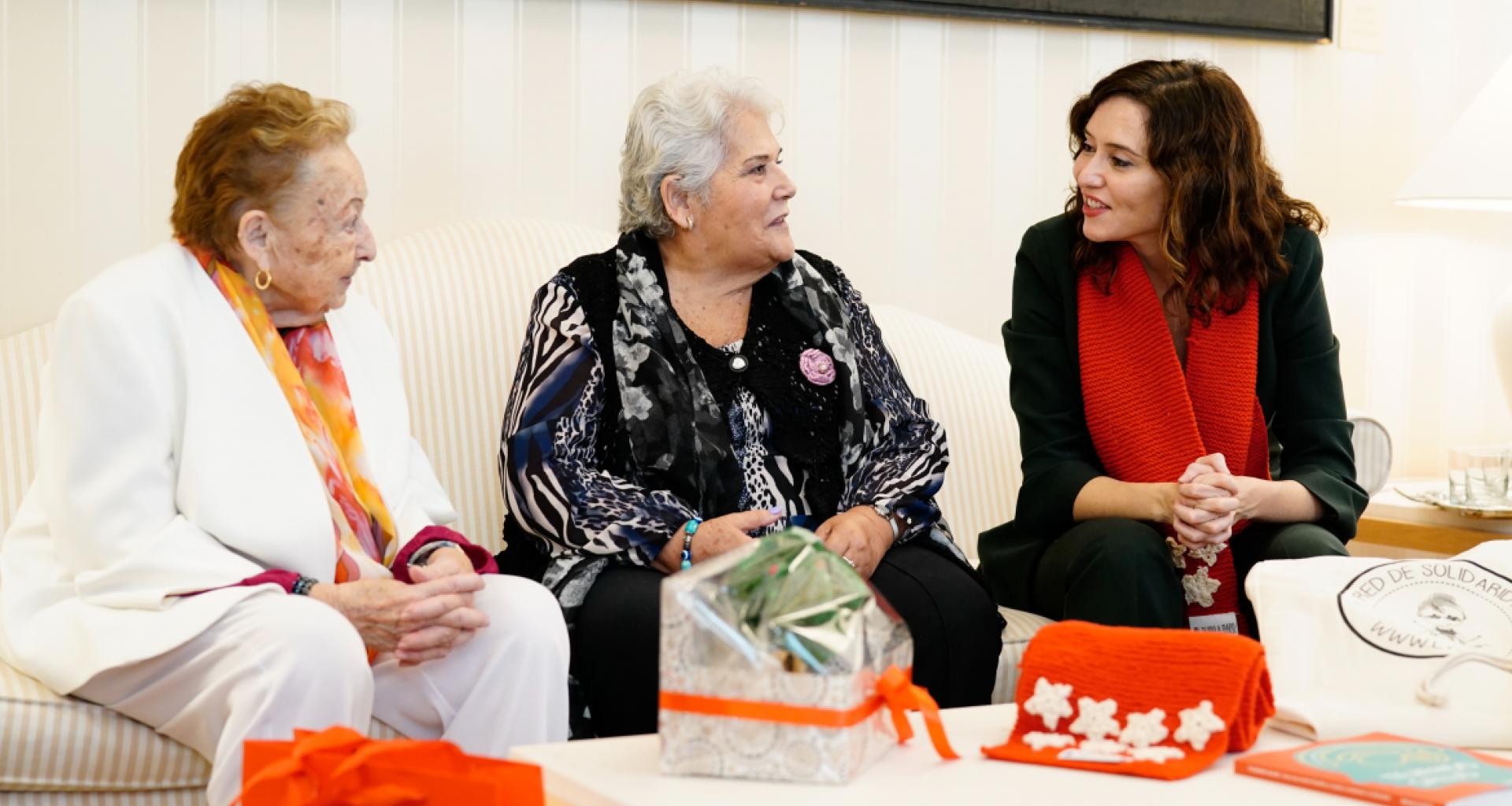 Isabel Díaz Ayuso, sonriente, conversando con dos residentes de la Residencia Nuestra Casa de Collado Villalba