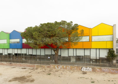 Vista exterior de la Fundación Nido, con un edificio de colores vibrantes como verde, azul, rojo, naranja y amarillo, rodeado de árboles