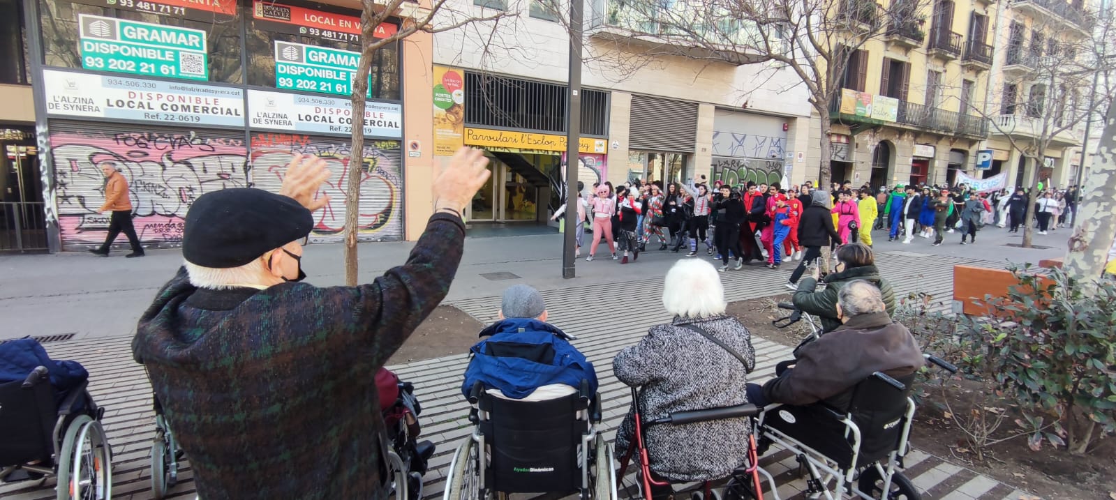 Los residentes en la calle observando un desfile con muchas personas vestidas con diferentes disfraces