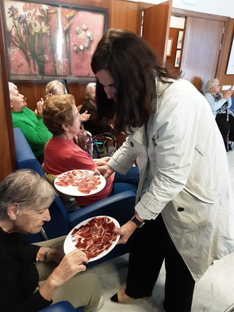 Carmen Parejo con una sonrisa ofreciendo jamón a los asistentes